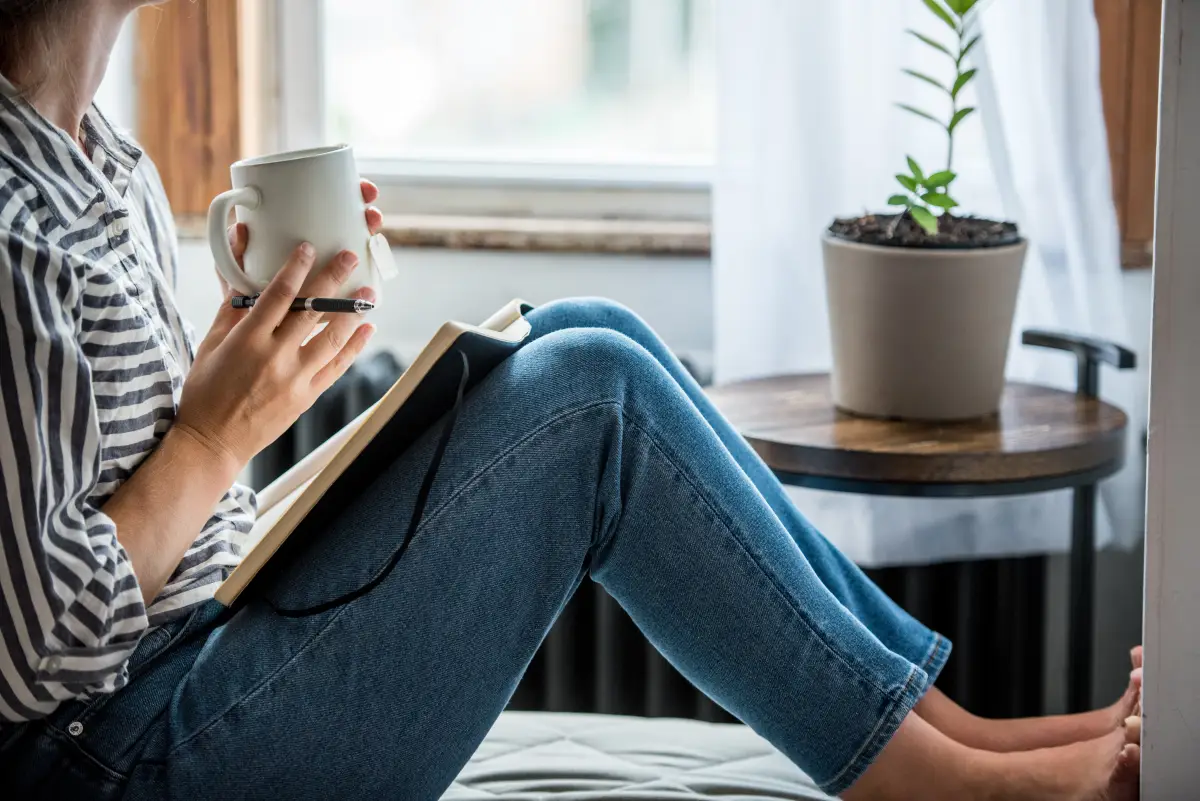 Mujer con taza de café y cuaderno 

