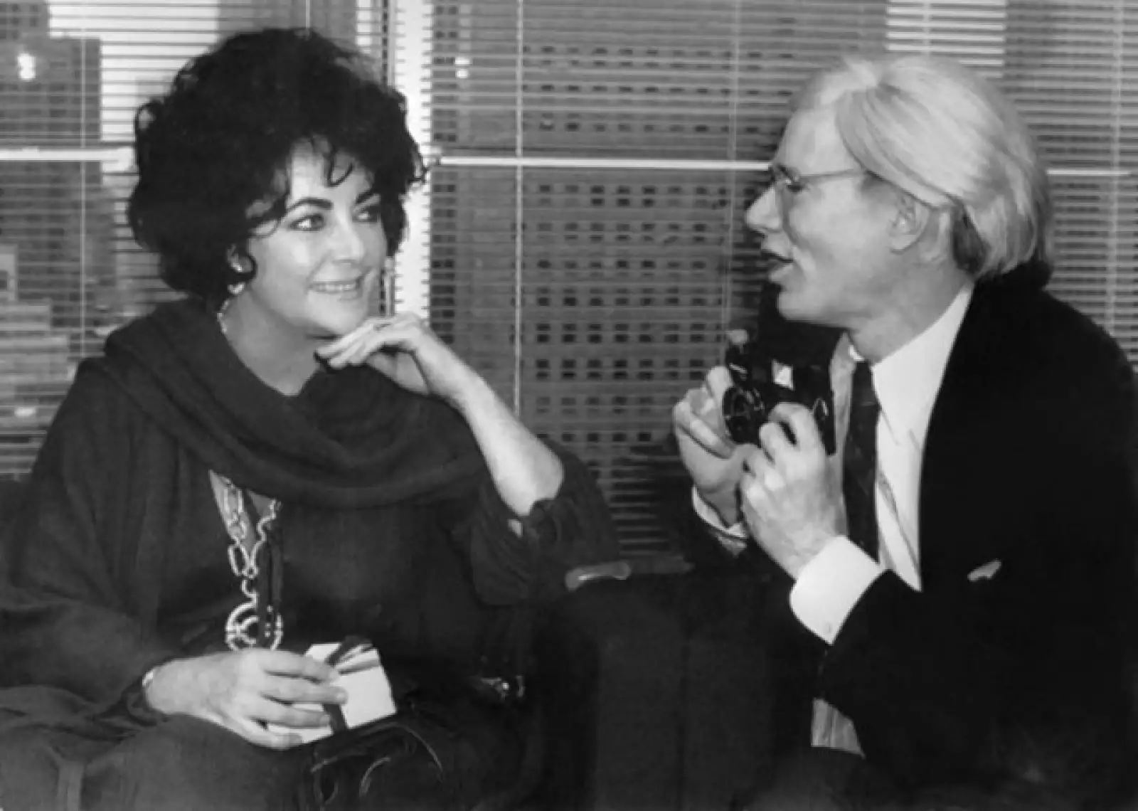 Andy Warhol preguntándole a John Warner – la actriz Elizabeth Taylor – si le permite tomarle una foto en la apertura del nuevo espacio del diseñador Halston en Nueva York, en 1978.