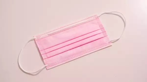 Un cubrebocas rosa sobre un fondo coral. 