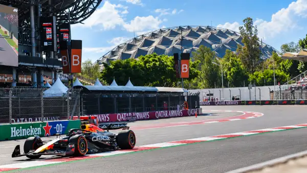 Auto de Fórmula 1 de Red Bull en una curva del Autódromo Hermanos Rodríguez, con el estadio y las gradas al fondo.