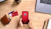 Una persona recibe la llamada de un estafador mientras realiza operaciones bancarias desde su teléfono móvil.