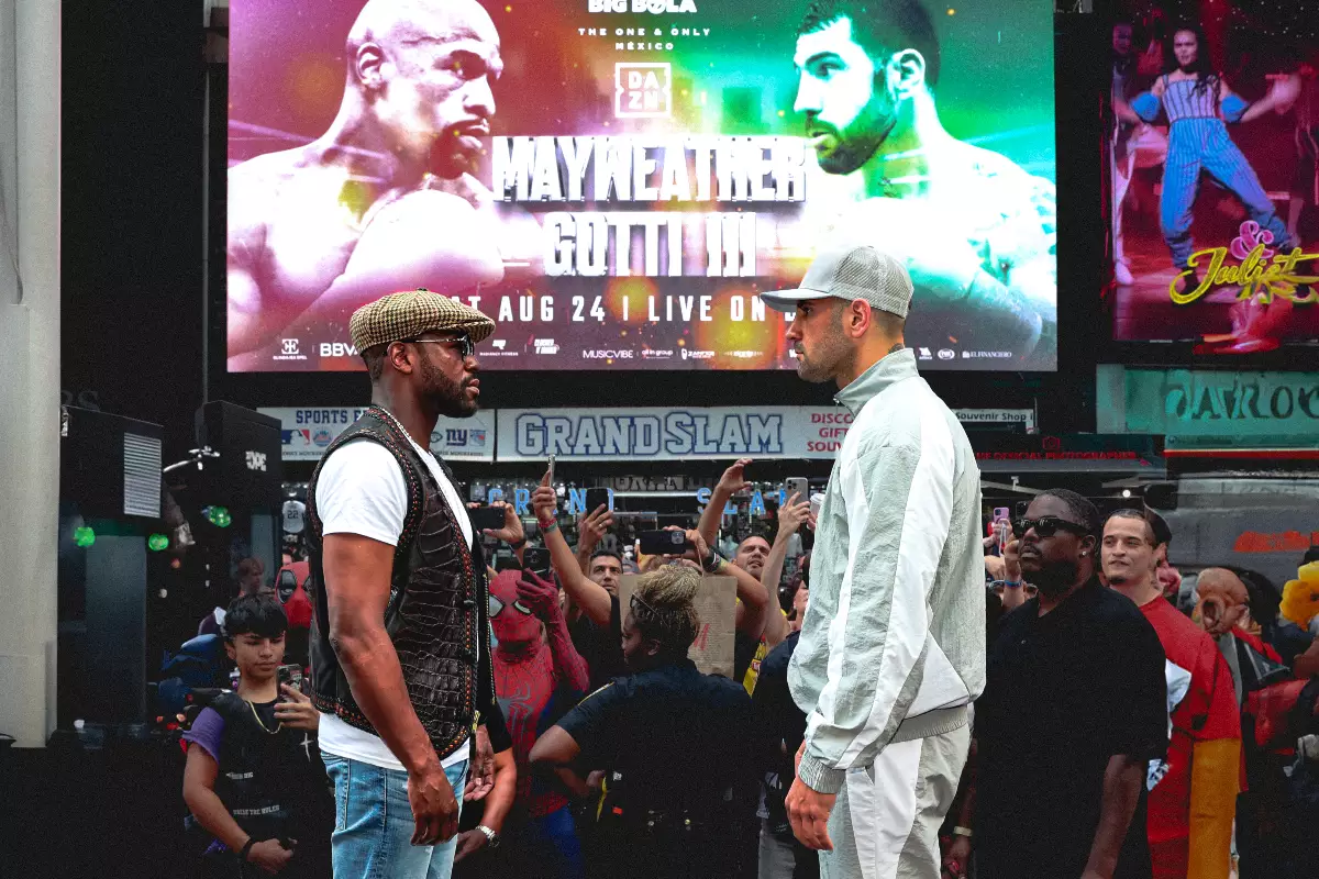 Foto de Mayweather y Gotti III frente a frente, de fondo se ve el cartel de la pelea que se realizará en cdmx