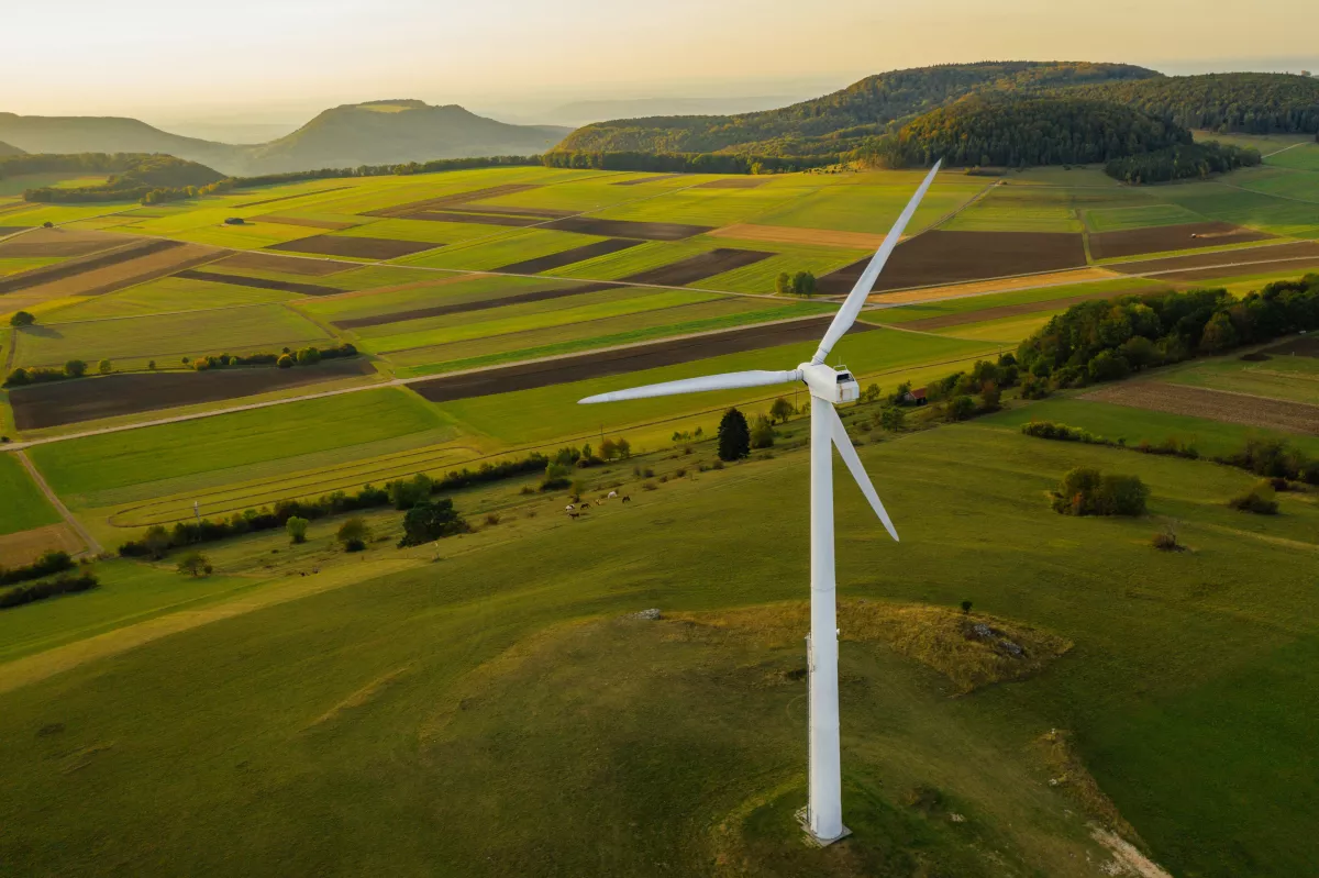 Alternative Energy Wind Turbine in Beautiful Green Landscape at Sunset