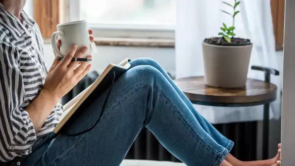 Mujer con taza de café y cuaderno
