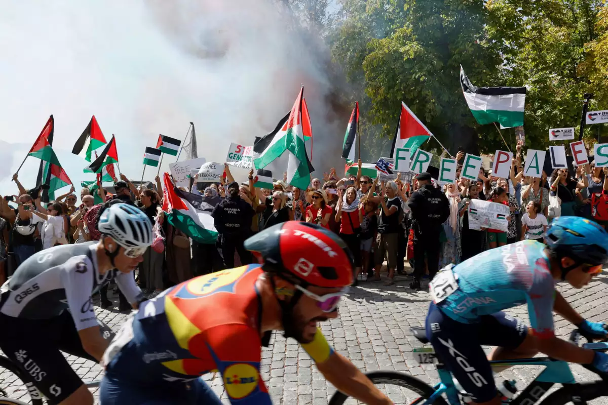 La manada cabalga mientras los manifestantes pro-palestinos sostienen banderas palestinas durante la etapa 20 de la Vuelta a España 2025, una carrera de 156 km entre Robledo de Chavela y Bola del Mundo, en El Escorial, el 13 de septiembre de 2025.