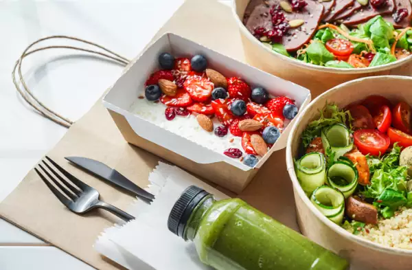 Healthy meal slimming diet plan daily ready menu background, organic fresh dishes and smoothie, fork knife on paper eco bag as food delivery courier service at home in office concept, close up view.