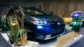Foto del Subaru Trailseeker en el estan de presentación, con las luces encendidas, destacando el emblema de Subaru iluminado.