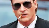 Joaquin Phoenix fumando y portando lentes oscuros. Un galán con aire de misterio.