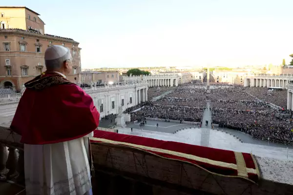 Foto desde el balcón papal del Papa León XIV de espalda y al frente miles de personas esperando la bendición en la Plaza de San Pedro, en el Vaticano.