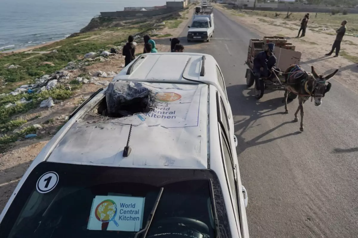 La gente se reúne alrededor del cadáver de un automóvil utilizado por el grupo de ayuda estadounidense World Central Kitchen, que fue alcanzado por un ataque israelí el día anterior en Deir al-Balah, en el centro de la Franja de Gaza, el 2 de abril de 2024, en medio de las batallas en curso entre Israel y el grupo militante palestino Hamás.