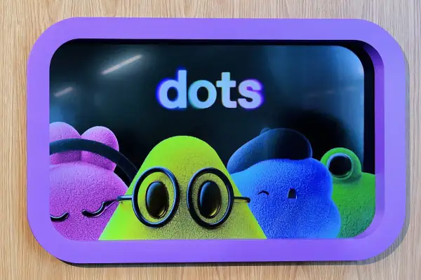 Cuatro personajes de apariencia afelpada y colores rosa, verde y azul aparecen dentro de una pantalla con marco morado. En el centro destaca una mascota verde con grandes lentes redondos y ojos negros. Sobre los personajes se lee la palabra "Dots".