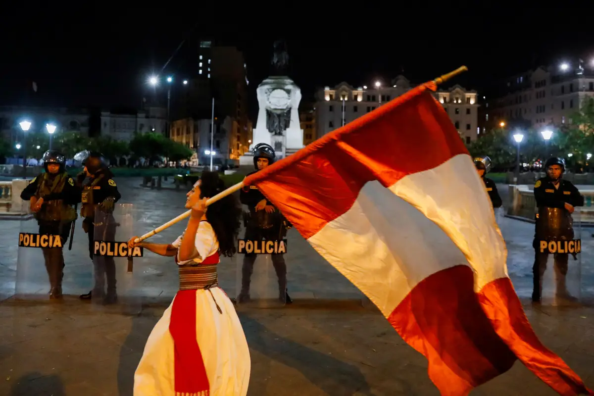 Las fuerzas de seguridad hacen guardia mientras un manifestante ondea la bandera de Perú durante una protesta para exigir la disolución del Congreso y elecciones democráticas, rechazando a Dina Boluarte como presidenta de Perú, luego del derrocamiento del presidente izquierdista Pedro Castillo, en Lima, Perú, el 12 de enero de 2023.