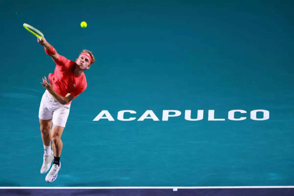Foto de Alejandro Davidovich con uniforme rojo y blanco a mitad de un salto lanzando la pelota con la raqueta y detrás en letras grandes "Acapulco".