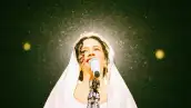 Retrato de Rosalía durante su concierto Lux Tour. En la imagen se ve a la cantante barcelonesa con un Manto blanco en la cabeza mientras interpreta el tema "Mio Cristo Piange Diamanti". 