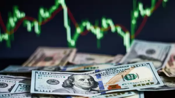 US dollar bills on a background with dynamics of exchange rates. Trading and financial risk concept