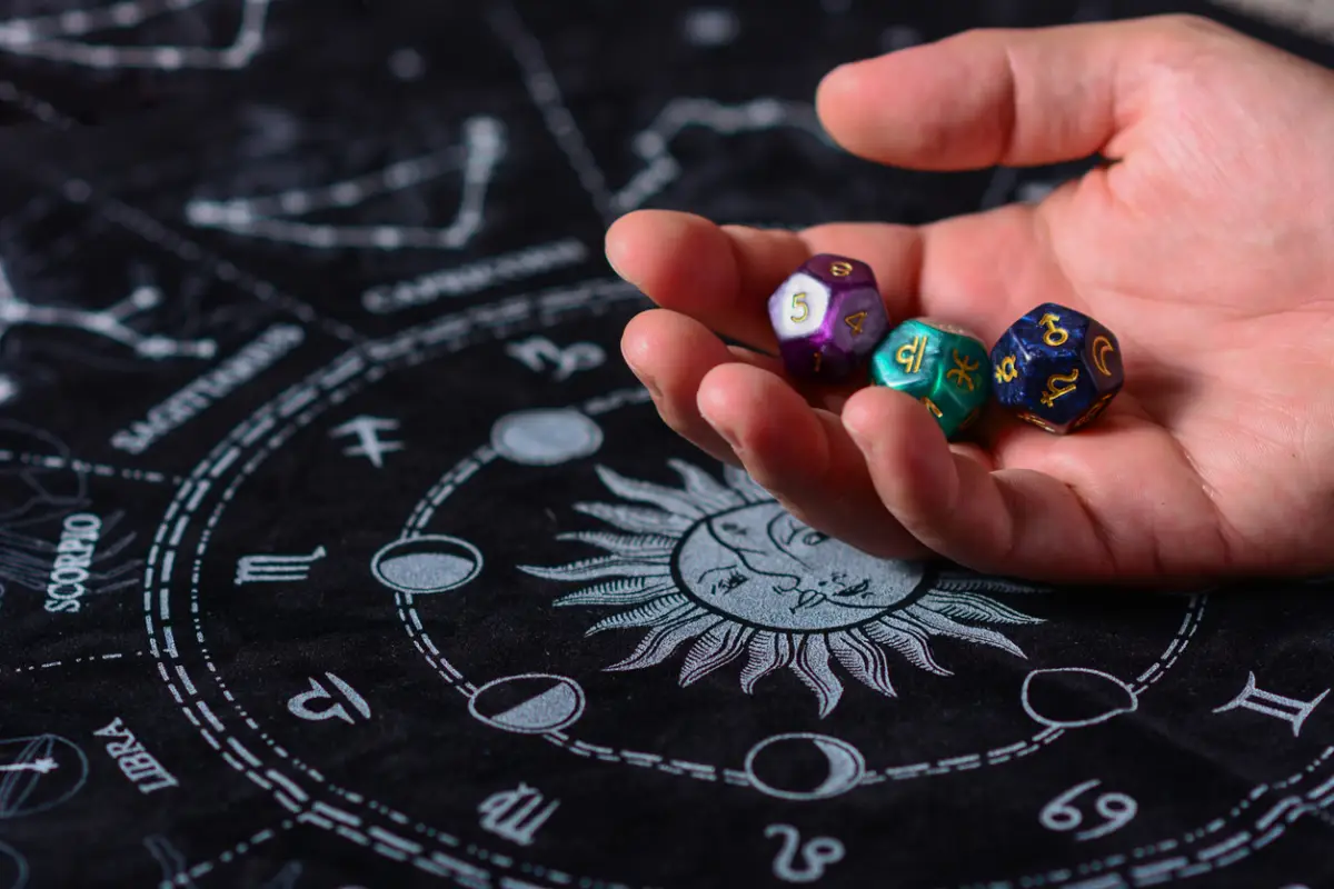 Manos con tres cubos de astrología con símbolos astrológicos sobre una tabla de zodiaco