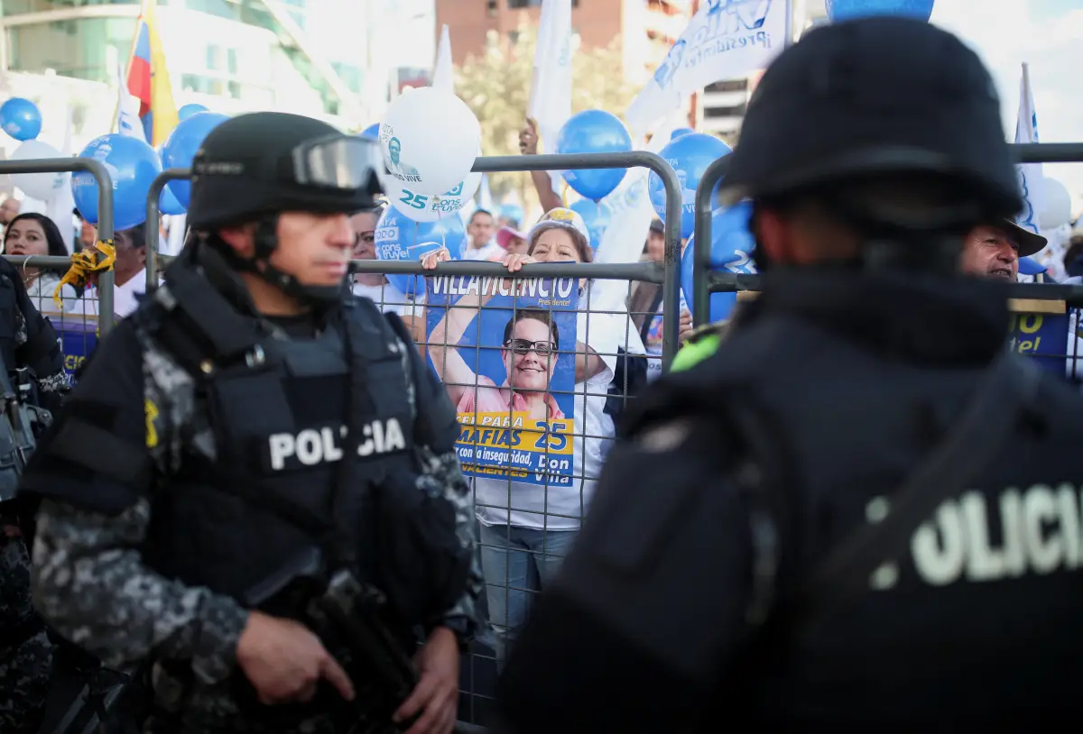 Los miembros de la policía hacen guardia mientras los partidarios sostienen carteles y globos con la foto del candidato presidencial asesinado Fernando Villavicencio el día del mitin de la campaña de clausura del candidato presidencial ecuatoriano Christian Zurita, que está reemplazando a Villavicencio, en Quito, Ecuador, el 17 de agosto de 2023.