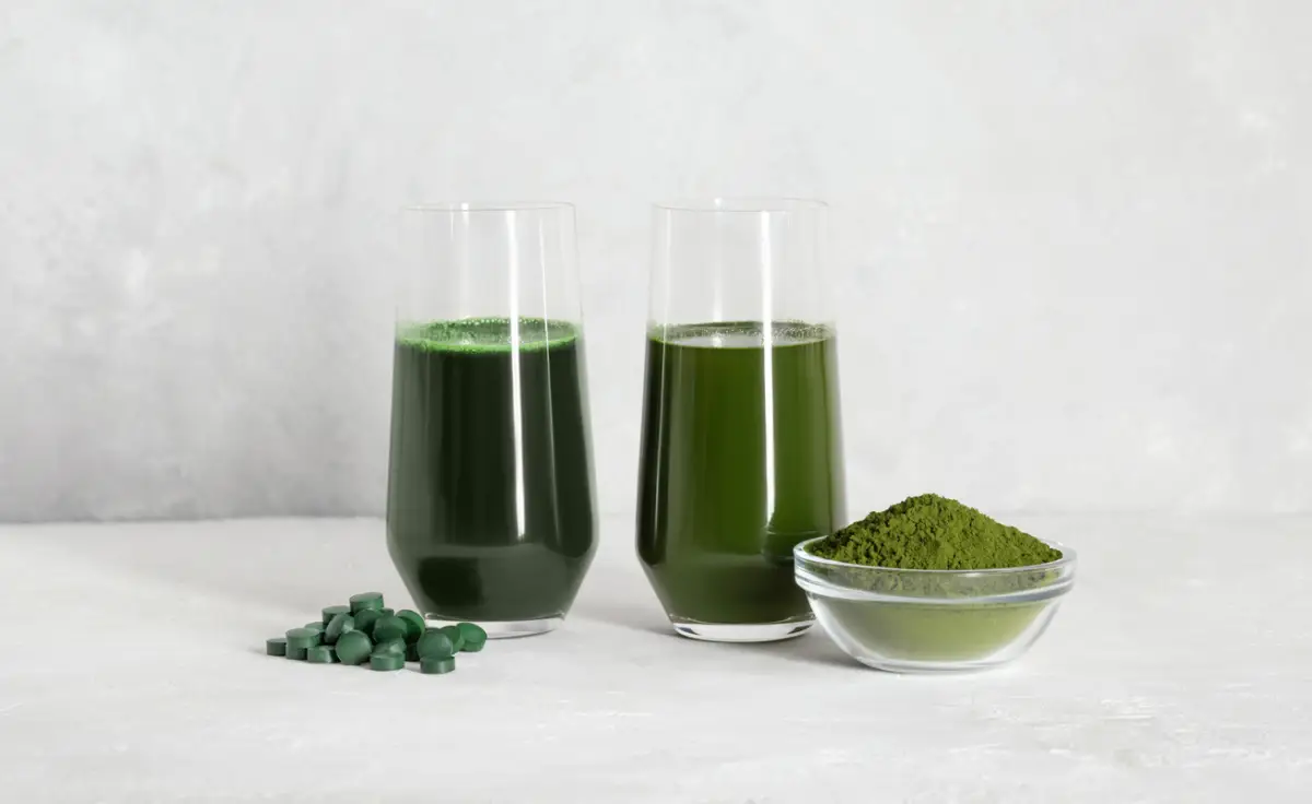 Chlorella and spirulina green drinks on a white concrete background. Spirulina tablets and chlorella powder. Superfood concept. Detox drinks. Copy space.