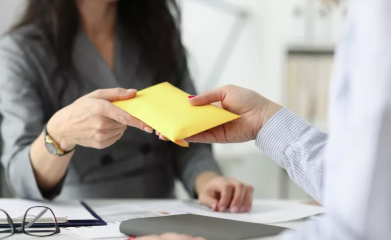 Mujer recibiendo sobre de dinero. Si se trabaja el 20 de noviembre, así como se debe pagar por ser festivo. 