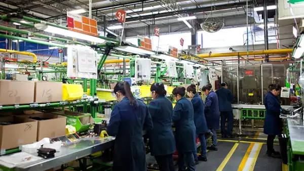 Vista de trabajadoras con los cuadernos de intrucciones del proceso, en la parte superior de su cabeza. Planta Schneider Electric