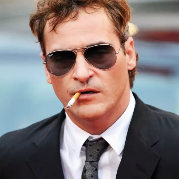 Joaquin Phoenix fumando y portando lentes oscuros. Un galán con aire de misterio.