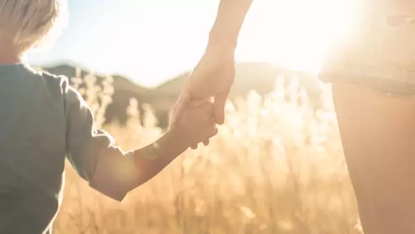 Niño de edad preescolar tomado de la mano de su mamá 