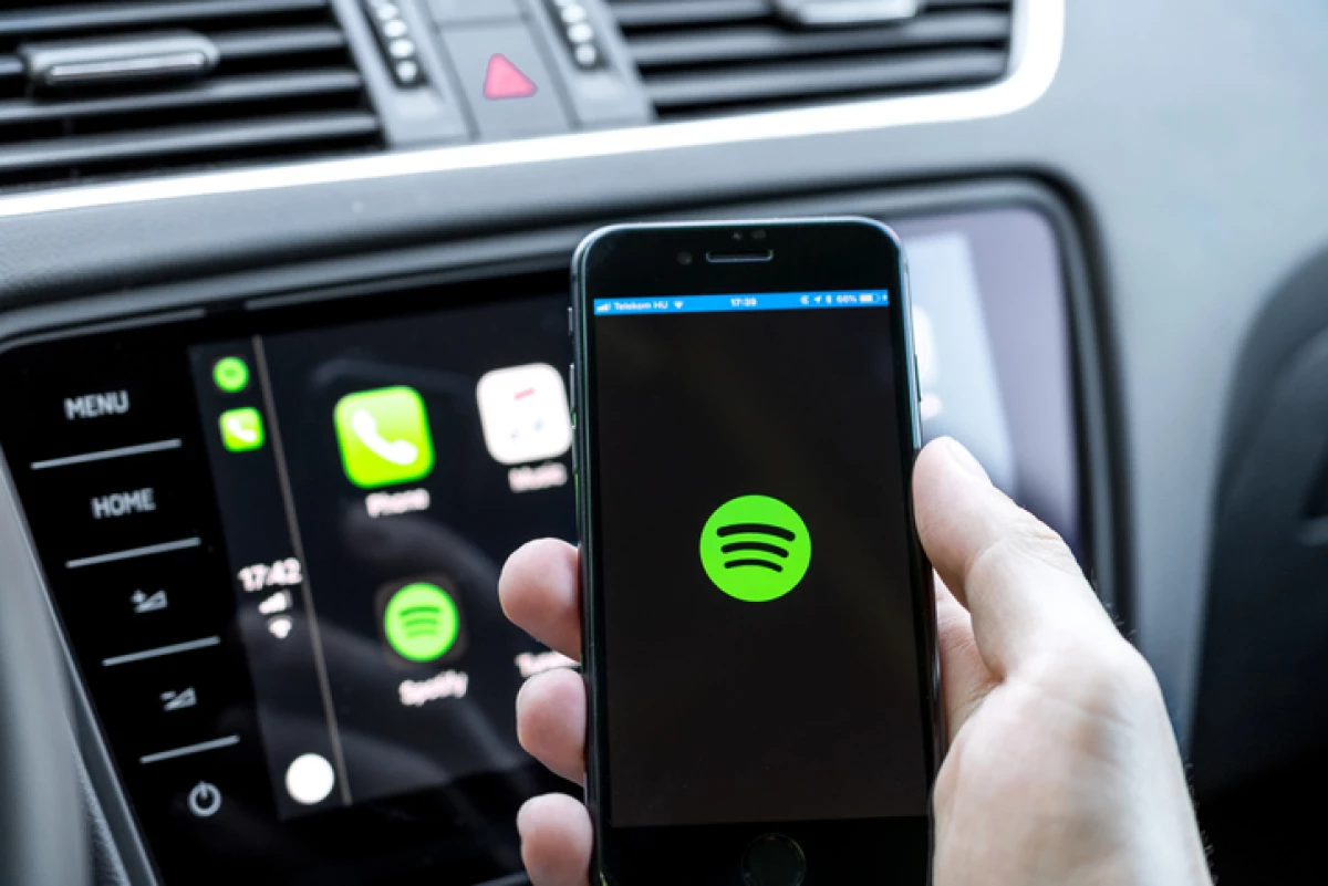 Male hands holding a smartphone that is connecting to the car's computer running the popular music streaming service