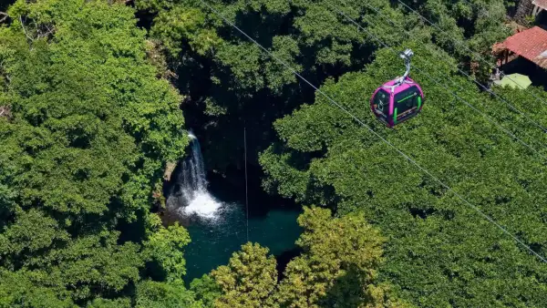 Una cabina del Teleférico de Uruapan atraviesa una zona boscosa con cascada.