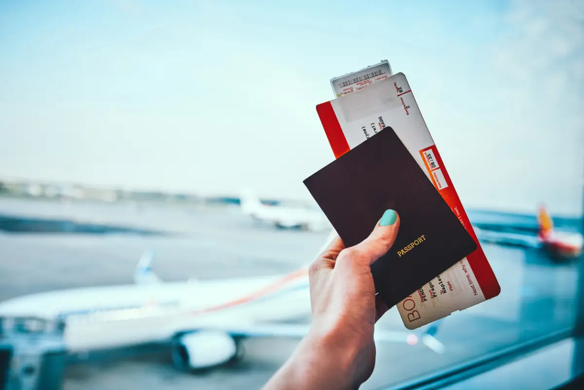 Captura recortada de una mujer irreconocible sosteniendo su pasaporte y boleto de avión antes de abordar su avión