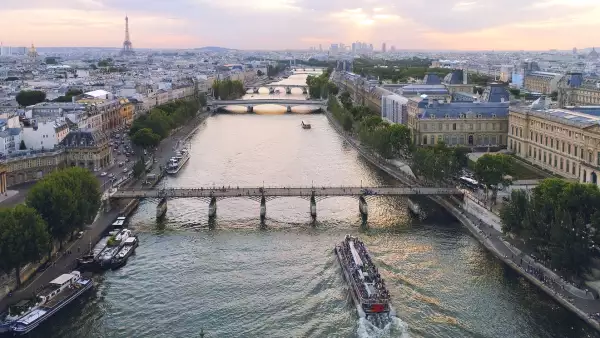 Foto panorámica del río Sena, en París, con el Museo del Louvre a la derecha y la torre Eiffel al fondo a la izquierda.
