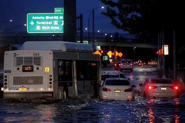 Un autobús pasa cerca de autos abandonados en una carretera inundada, después de que los remanentes de la tormenta tropical Ida provocaran históricas lluvias en Nueva York y Nueva Jersey.