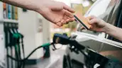 Un usuarios cargando combustible en una estación de servicio mientras el despachador cobra al usuario con tarjeta.