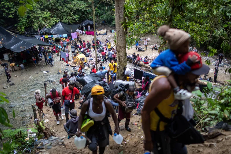 Familias inmigrantes de Haití suben un empinado sendero de montaña cerca de la frontera con Panamá en el segundo día de su viaje el 19 de octubre de 2021 a través del Darien Gap, Colombia. El paso de 66 millas a través de la densa selva tropical y las montañas se considera el tramo más difícil para los migrantes que viajan desde América del Sur a los Estados Unidos. Los guías los acompañan en la caminata de dos días hasta la frontera con Panamá, luego de lo cual están solos para una caminata adicional de varios días cuando son más vulnerables a los bandidos y otros peligros en el camino. Más de 70.000 migrantes han viajado por el Tapón del Darién este año, según las autoridades panameñas. La mayoría de los migrantes de los últimos meses han sido haitianos, muchos de los cuales vivían en Chile y Brasil desde el terremoto de Haití de 2010. El Tapón de Darién, que conecta América del Norte y América del Sur, es donde la Carretera Panamericana nunca se completó debido a la dificultad del terreno, el alto costo y una miríada de preocupaciones ambientales. 