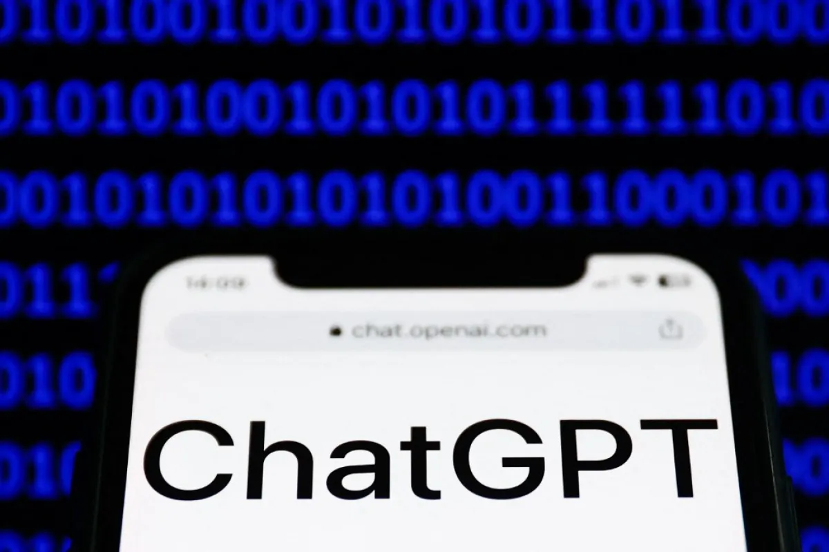 El sitio web de ChatGPT se muestra en la pantalla de un teléfono y un código binario se muestra en una pantalla de fondo.