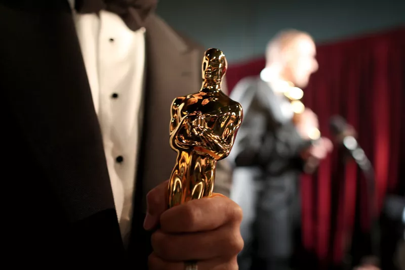 Foto de un close up de una estatuilla del Oscar en manos de un hombre.