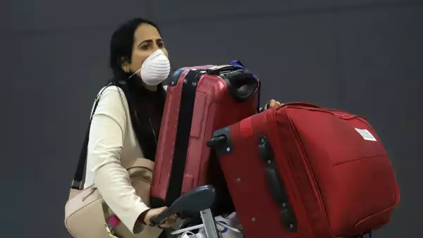 A woman wears a protective face mask at international arrivals area at Guarulhos International Airport in Guarulhos