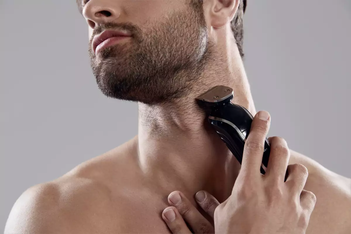 Foto de un hombre rasurando su barba con una afeitadora eléctrica.