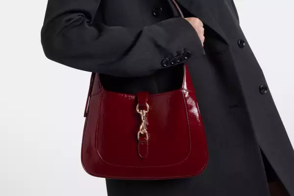 foto del bolso gucci ancora en color vino, una modelo de gabardina negra lo lleva bajo el brazo
