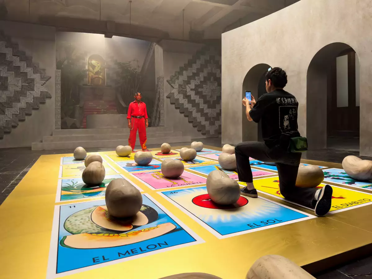 Foto del detrás de cámaras del cortometraje 'Suerte' en el que se observa una tarjeta de lotería gigante en el suelo y el personaje del Diablito al fondo