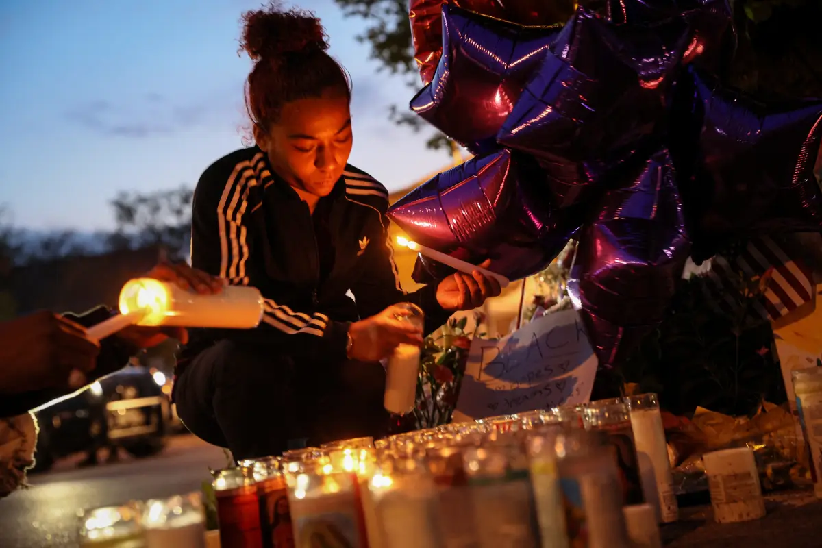 Una mujer prende una vela en un memorial por las víctimas de un tiroteo en el supermercado Tops en Buffalo, Nueva York. 