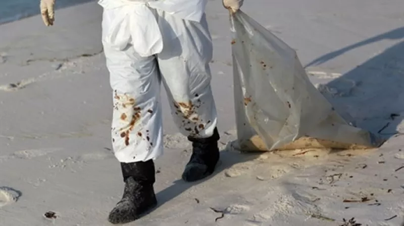 Un hombre camina por una playa contaminada por petroleo