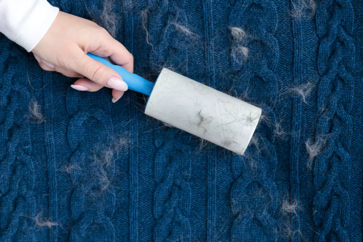 Woman hand using a sticky roller to clean fabrics