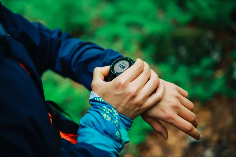 trail runner checking her smart watch in the forest