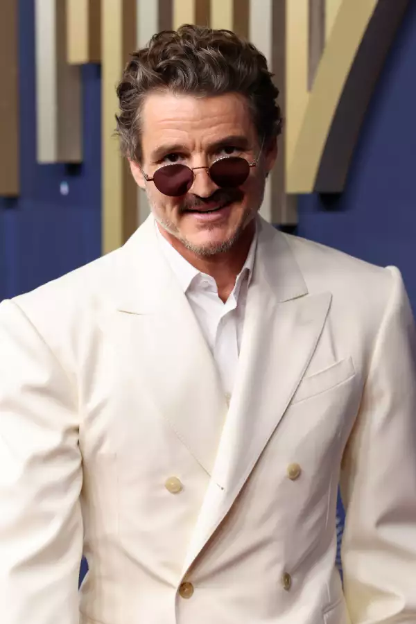 Foto de Pedro Pascal en los Emmy Awards 2025 con traje color hueso y camisa blanca y lentes oscuros redondos.