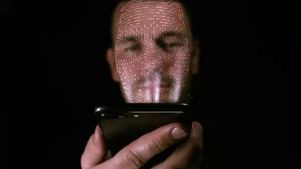 Male using his smart phone with facial recognition unlock. 3D mesh print is projected onto his face.