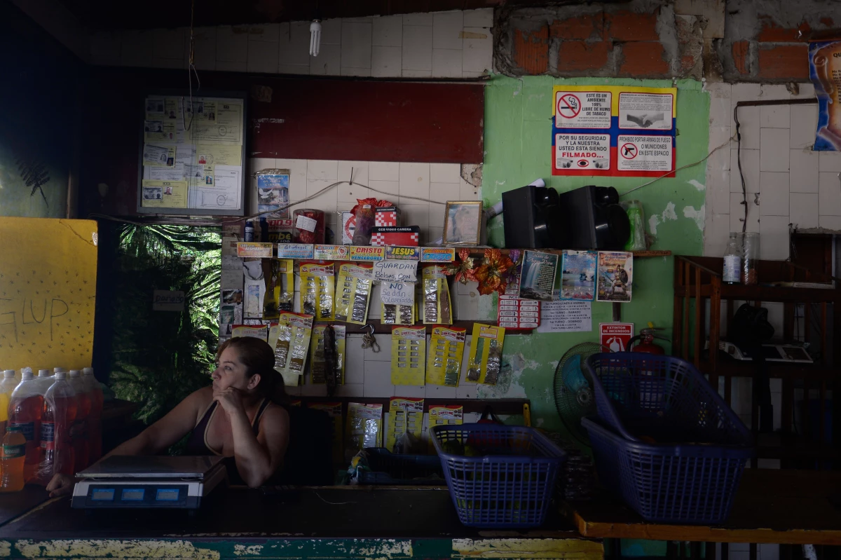 Una mujer hace una pausa en sus actividades en una tienda en Miranda durante uno de los cortes de luz que se aplican en todo el país.