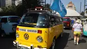 Combi amarilla con bandera de VW transita frente al Monumento a la Revolución.