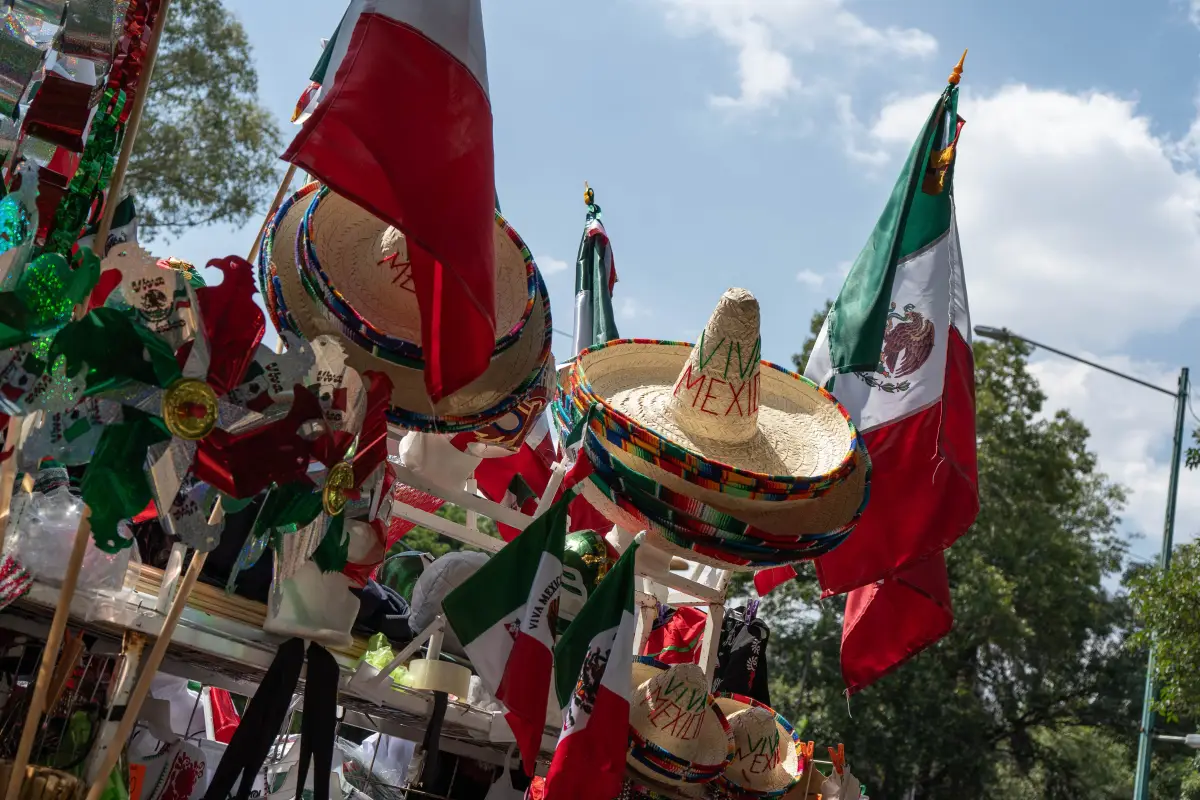 Carro de venta de artículos patrios se instala en la colonia Roma Norte. Hay sombreros, banderas y regiletes. 