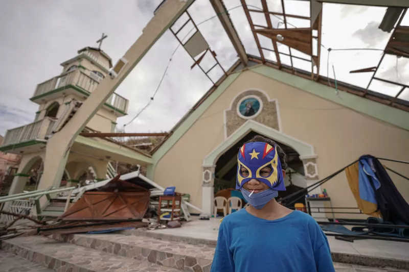 Un niño con una máscara disfrazada sonríe frente a una iglesia que se utiliza como refugio improvisado el 21 de noviembre de 2020 en la isla de Providencia, Colombia.