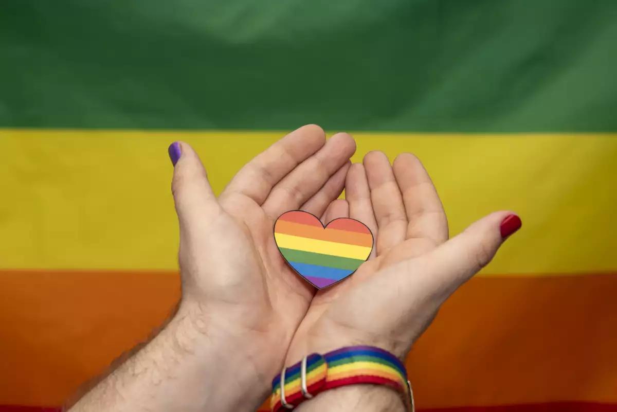 manos sosteniendo la bandera lgbt en forma de corazón sobre un fondo de arco iris